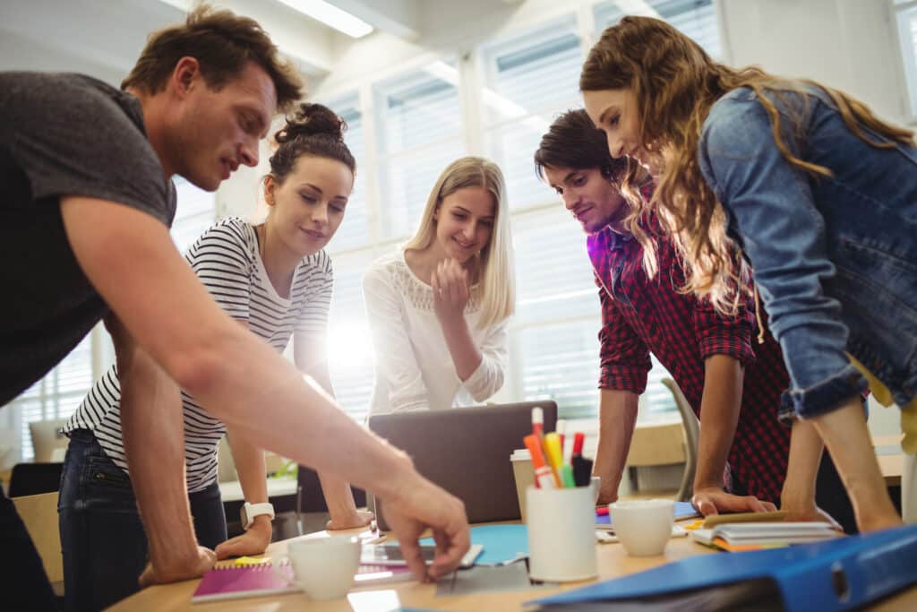 Grupo de pessoas reunidos em uma mesa realizando um brainstorm.